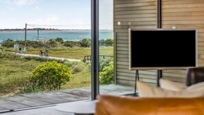 Une chambre moderne dotée d’une grande fenêtre donnant sur une plage et la mer.