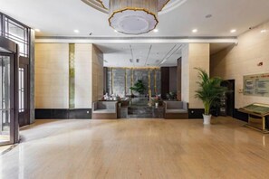 A spacious lobby with a marble floor, a reception desk, and a chandelier. - Huating Hotel (Huzhou)