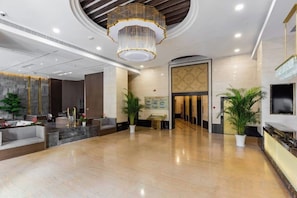 A spacious lobby with a marble floor, a large chandelier, and a reception desk. - Huating Hotel (Huzhou)