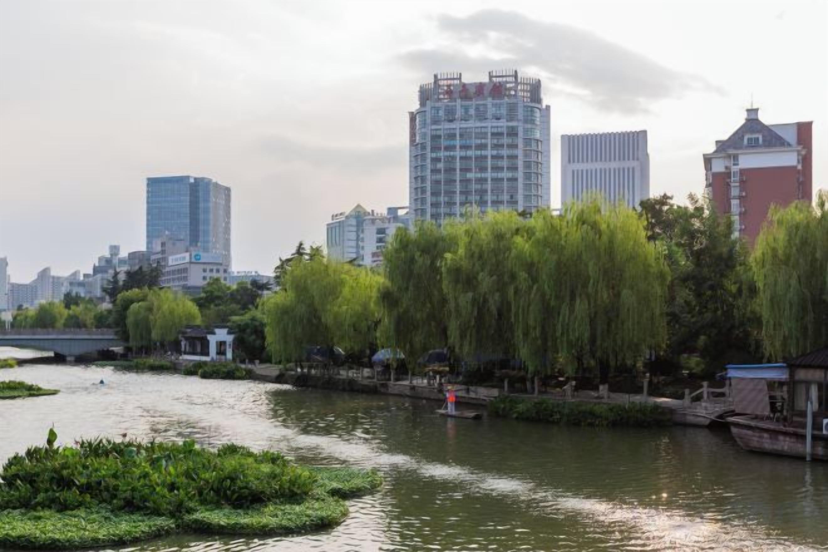 A river with a bridge, buildings, and trees.