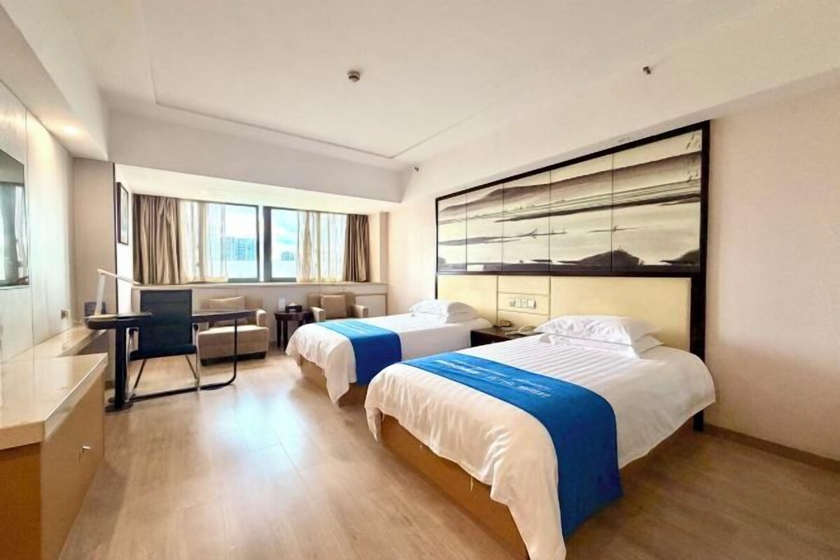 Ett hotellrum med två sängar, ett skrivbord och en stol.