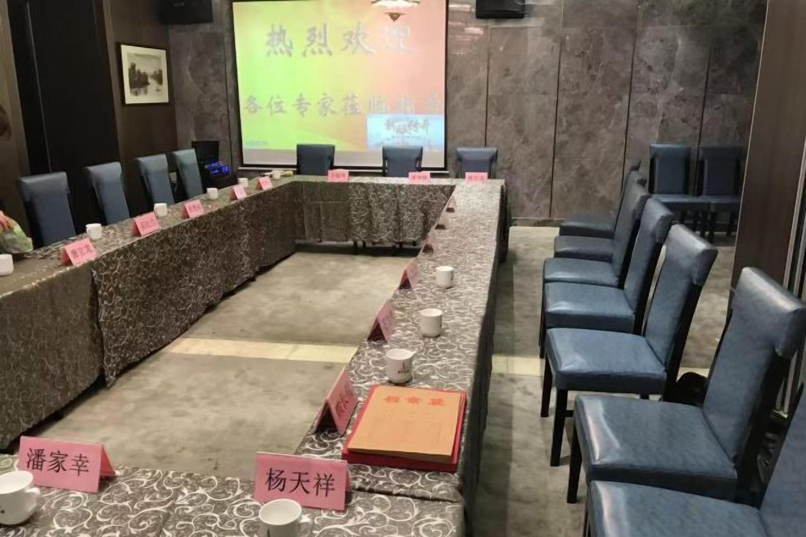 A conference room with a long table, chairs, nameplates, and a presentation screen.
