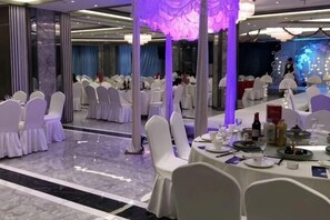A banquet hall with round tables, white chairs, and purple lighting. - Huating Hotel (Huzhou)