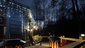 A wooden deck with a railing, a lantern, and string lights. - RiverFront Retreat/Fenced/LOVEDogsStayForFree/KingBeds/Sauna+SteamShower (Ellijay)