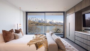 Een slaapkamer met een groot raam en uitzicht op de bergen.