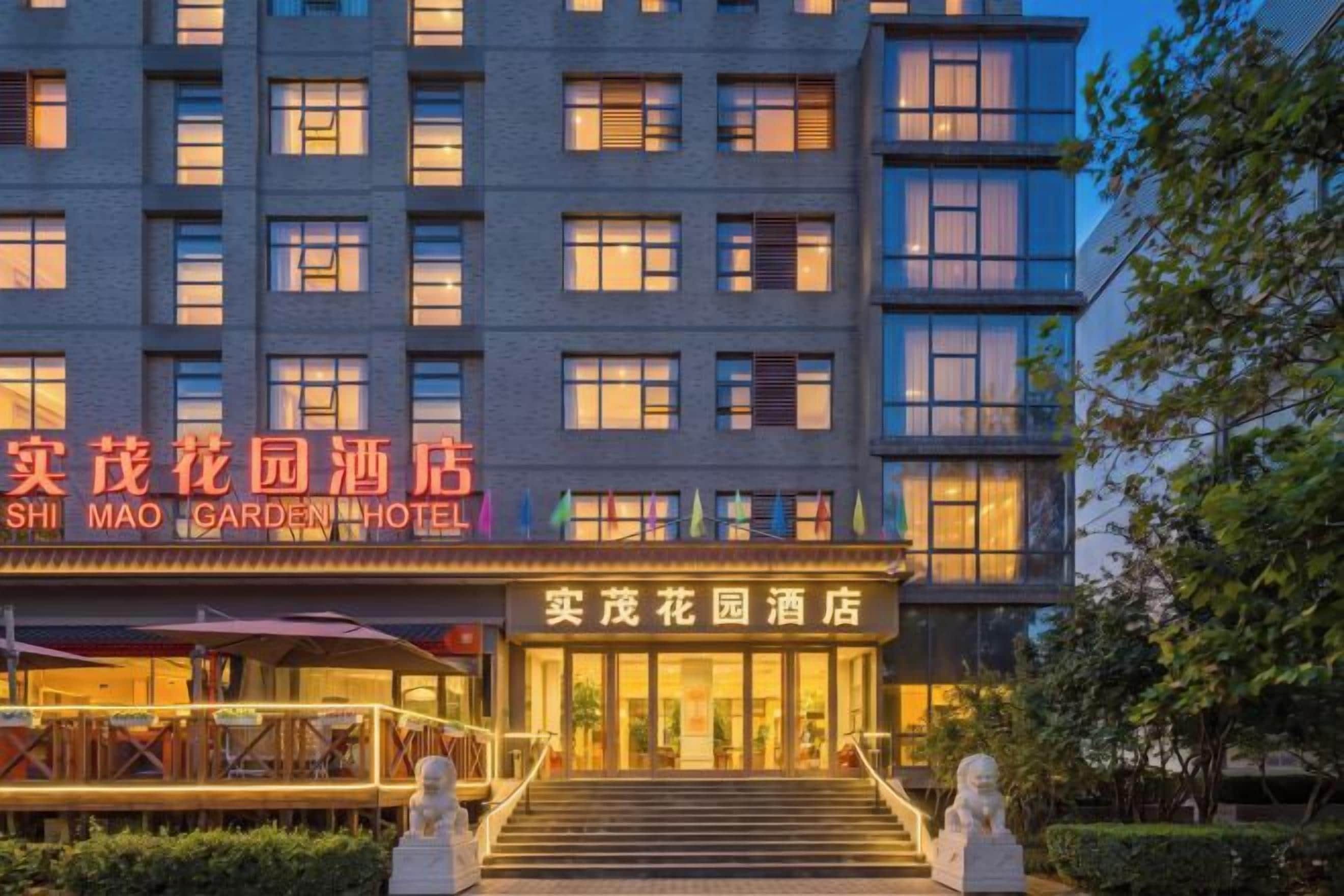 A multi-story hotel with a prominent entrance, signage in two languages, and a well-lit facade.
