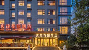 A multi-story hotel with a prominent entrance, signage in two languages, and a well-lit facade.