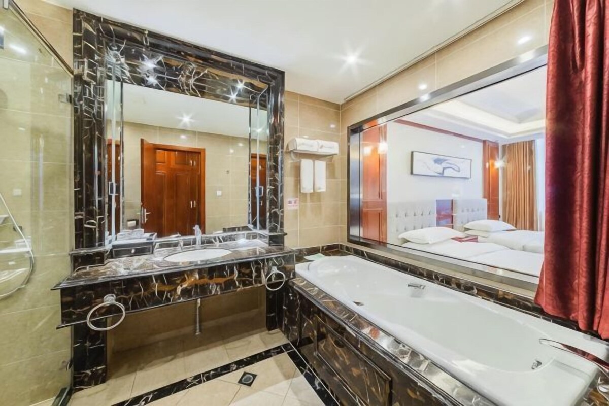 A bathroom with a large mirror, a bathtub, and a vanity with a sink.