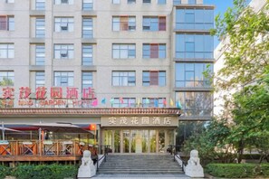 A multi-story hotel with a prominent entrance, a garden area, and a visible restaurant. - Shi Mao Garden Hotel (Beijing)