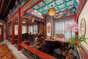 Interior de un restaurante chino tradicional con muebles de madera, pilares rojos y un techo decorativo.
