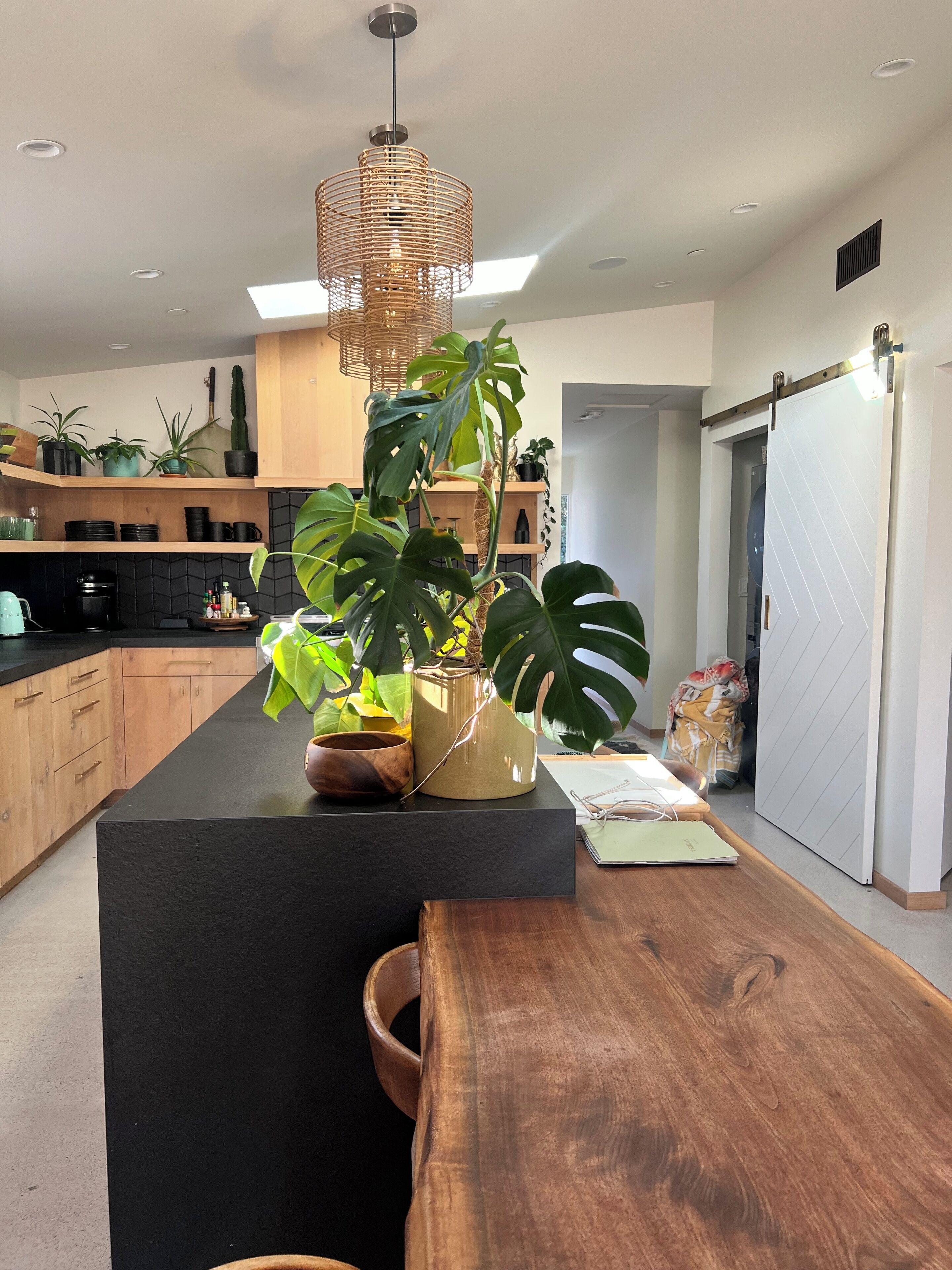 Una cucina moderna con un piano di lavoro nero, mobili in legno e una grande isola con una pianta.