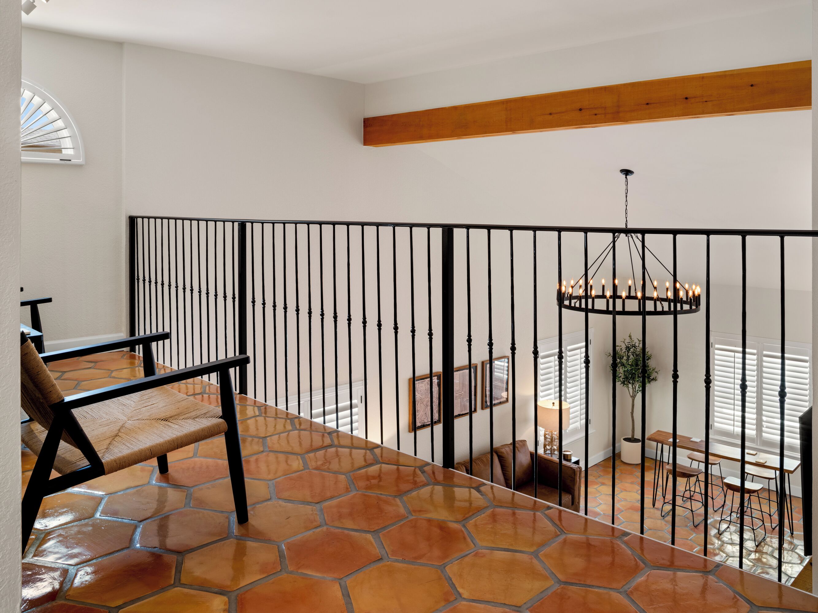 Ein geräumiger Balkon mit Fliesenboden, Holzbalkendecke und einem Geländer aus schwarzem Metall.