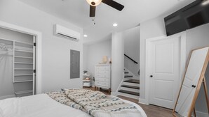 Un dormitorio con una cama, un aparador, un armario, una escalera y un televisor montado en la pared.