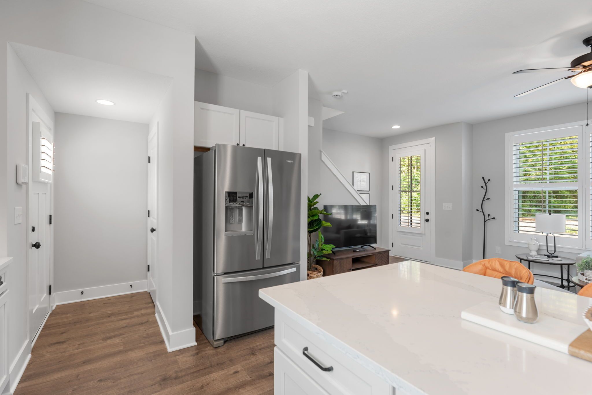 A modern kitchen with white cabinetry, a stainless steel refrigerator, and a marble countertop.