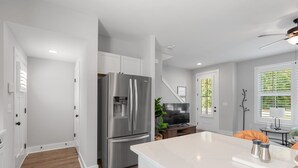 Una cocina moderna con armarios blancos, un refrigerador de acero inoxidable y una encimera de mármol.