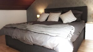 A bedroom with a large bed, dark headboard, and a patterned blanket.