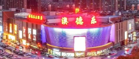 A large, circular building with illuminated signage, surrounded by a parking lot and urban buildings.