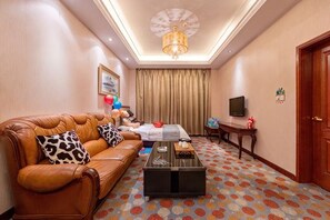 Ein Hotelzimmer mit einer Ledersofa, einem Couchtisch, einem Fernseher und einem gemusterten Teppich.