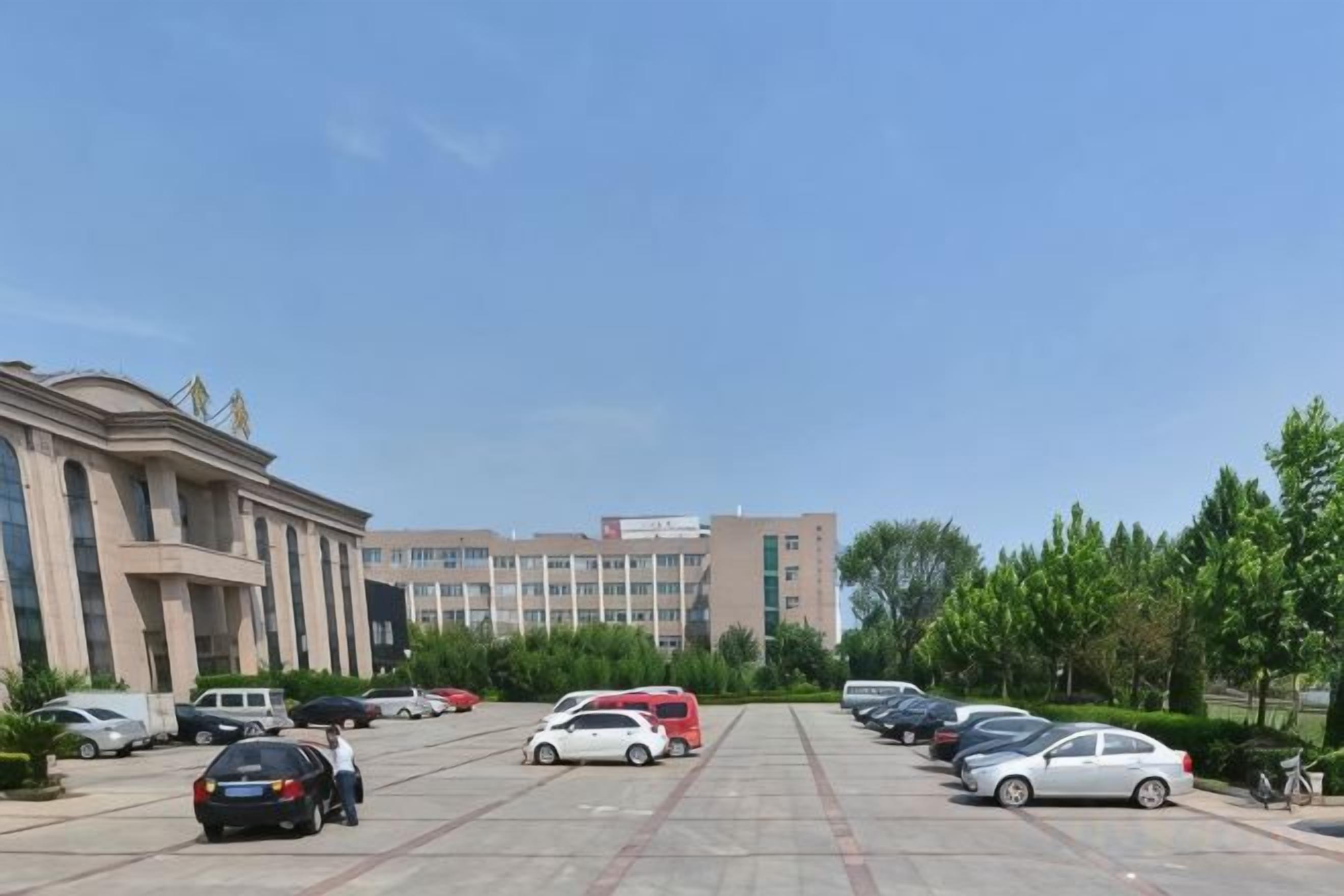 A parking lot with multiple cars, a building with classical architecture, and a clear sky.