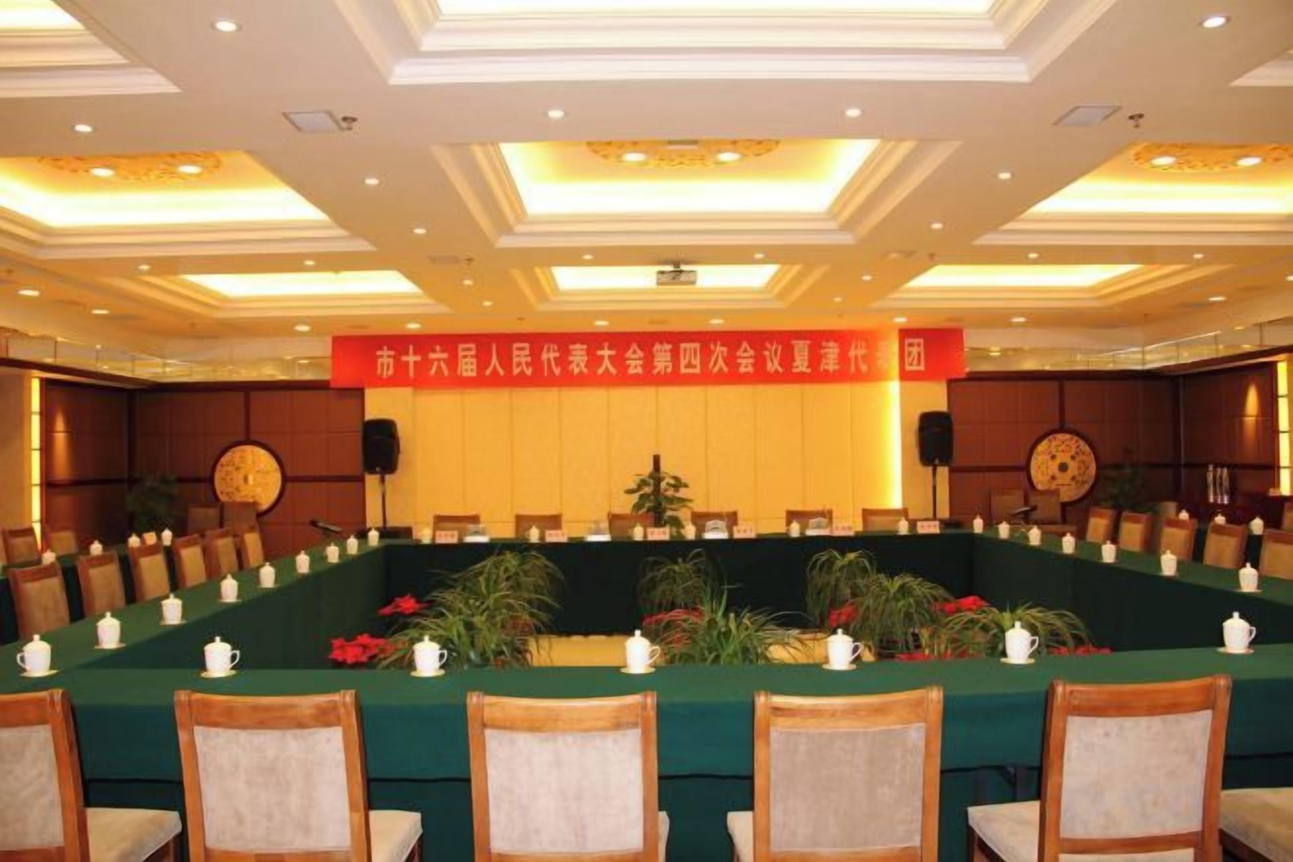 Une salle de conférence avec une longue table, des chaises et une banderole.