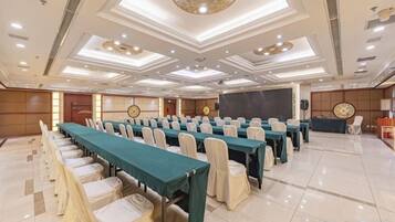 A conference room with rows of tables and chairs, a stage, and a podium.