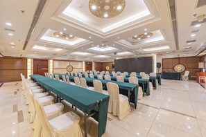 A conference room with rows of tables and chairs, a stage, and a podium. - Kaiyuan Hot Spring Resort (Dezhou)