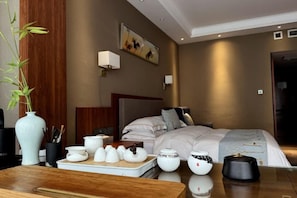 A hotel room with a bed, bedside table, and a vase with plants. - Kaiyuan Hot Spring Resort (Dezhou)