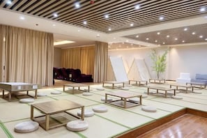 A room with tatami mats, wooden tables, and chairs, a large window, and a ceiling with recessed lighting. - Kaiyuan Hot Spring Resort (Dezhou)