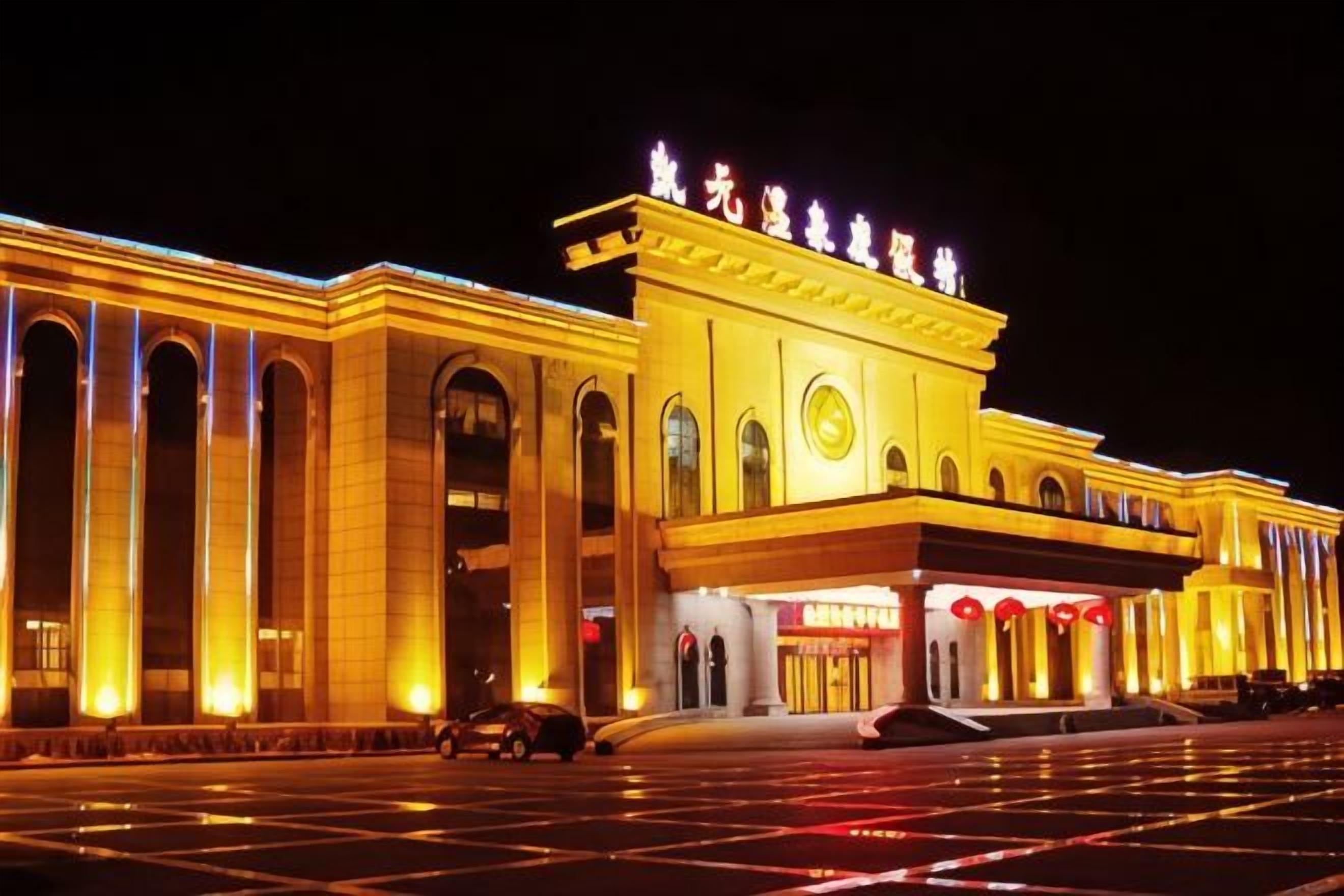 A large, illuminated building with a prominent entrance and multiple columns.