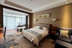 A hotel room with a large bed, a sofa, a desk, and a view of the outdoors. - Kaiyuan Hot Spring Resort (Dezhou)