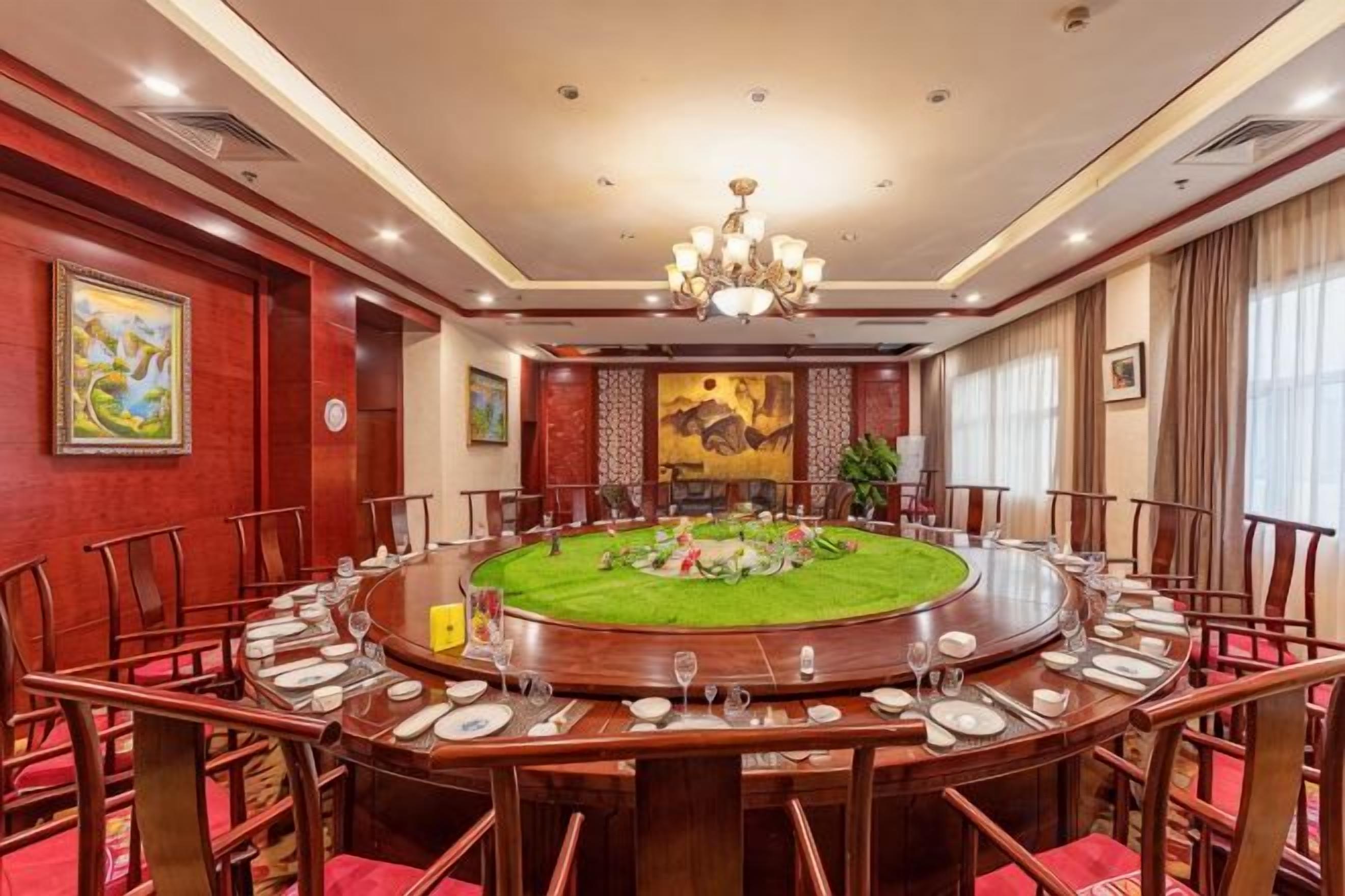 A conference room with a round table, chairs, and a chandelier.