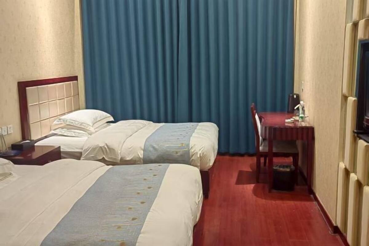 Een hotelkamer met twee bedden, een bureau en een stoel.