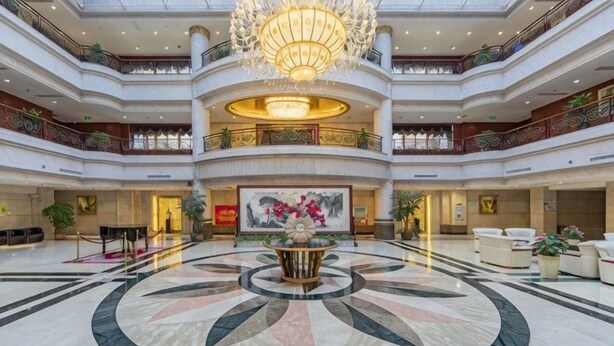 A multi-level hotel lobby with a central circular marble floor, a large chandelier, and a prominent artwork on the wall. - Kaiyuan Hot Spring Resort (Dezhou)