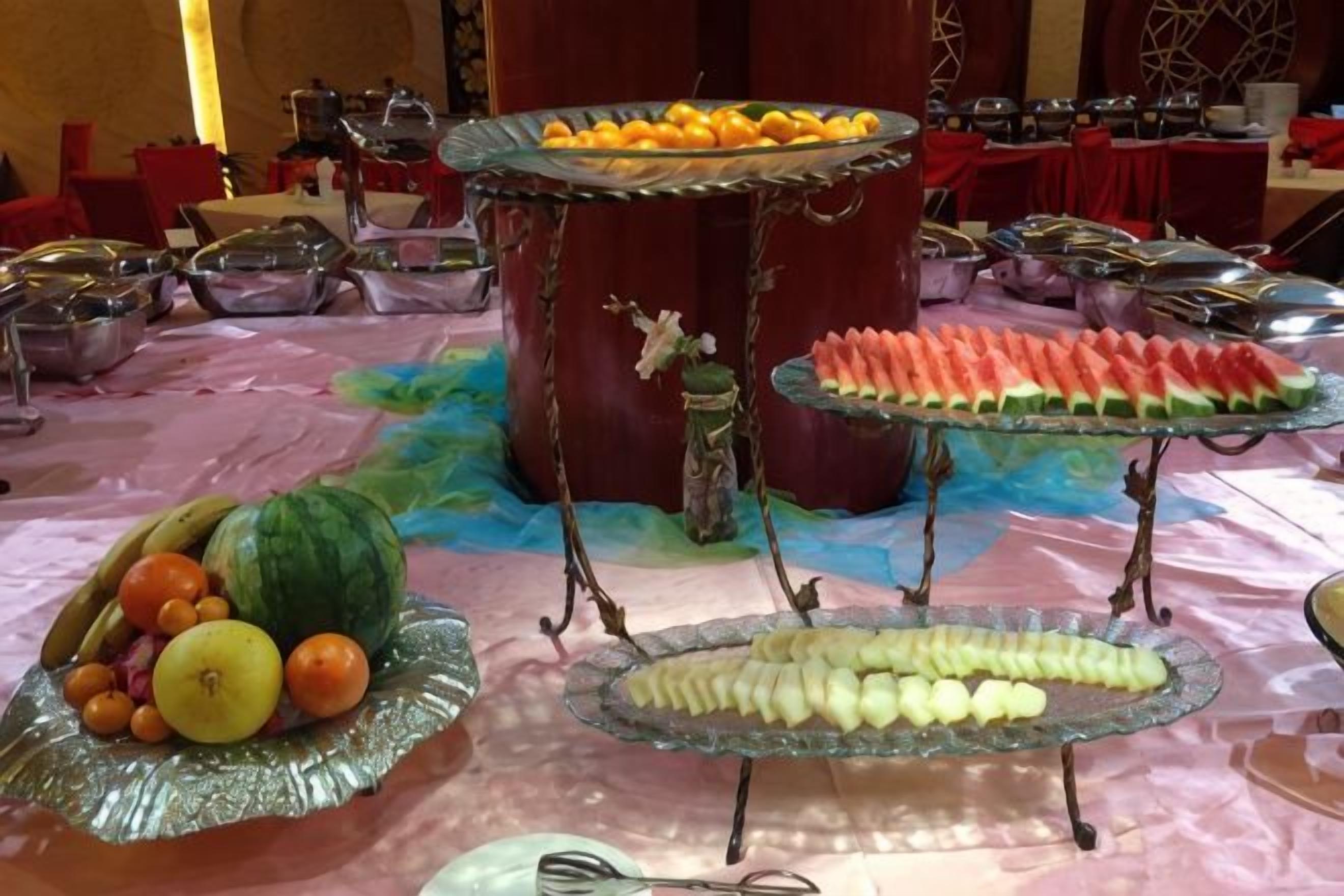 A buffet table with various food items, including fruits and vegetables, arranged on glass stands.