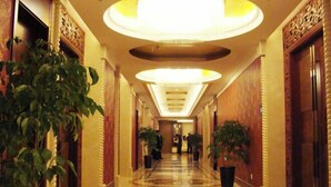 A hotel hallway with a polished marble floor, large circular ceiling lights, and potted plants. - Kaiyuan Hot Spring Resort (Dezhou)