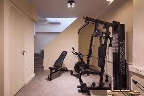 Une salle de sport à domicile équipée d’un banc, d’un vélo d’appartement et d’un appareil de musculation.