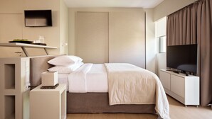 A modern hotel room with a bed, bedside table, TV, and a wall-mounted shelf. - Momo Suites Acropolis by Aura Homes (Athens)