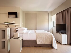 A modern hotel room with a bed, bedside table, TV, and a wall-mounted shelf. - Momo Suites Acropolis by Aura Homes (Athens)