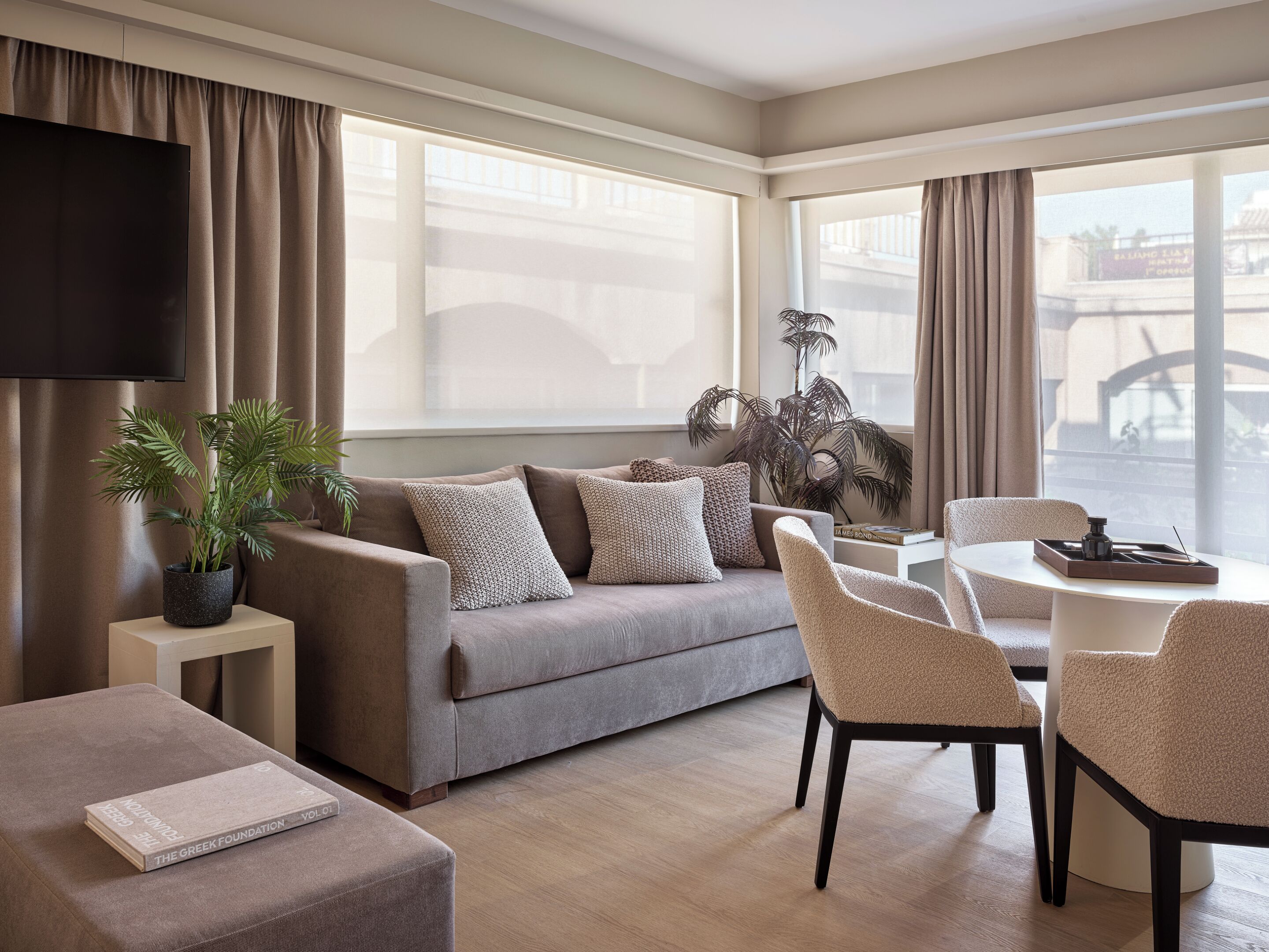 A modern living room with a sofa, armchairs, a coffee table, and a television.