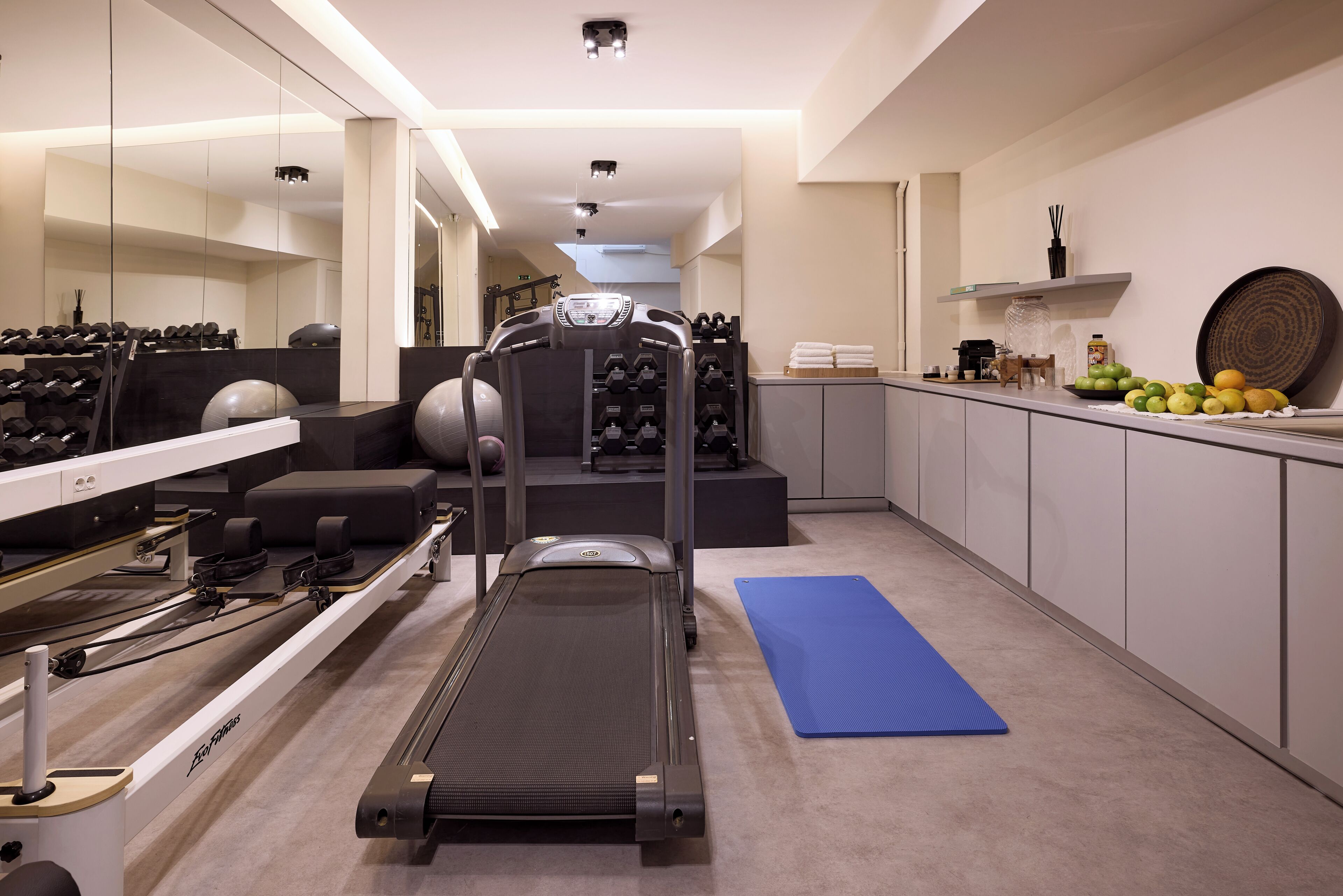 A home gym with a treadmill, weights, and exercise equipment.