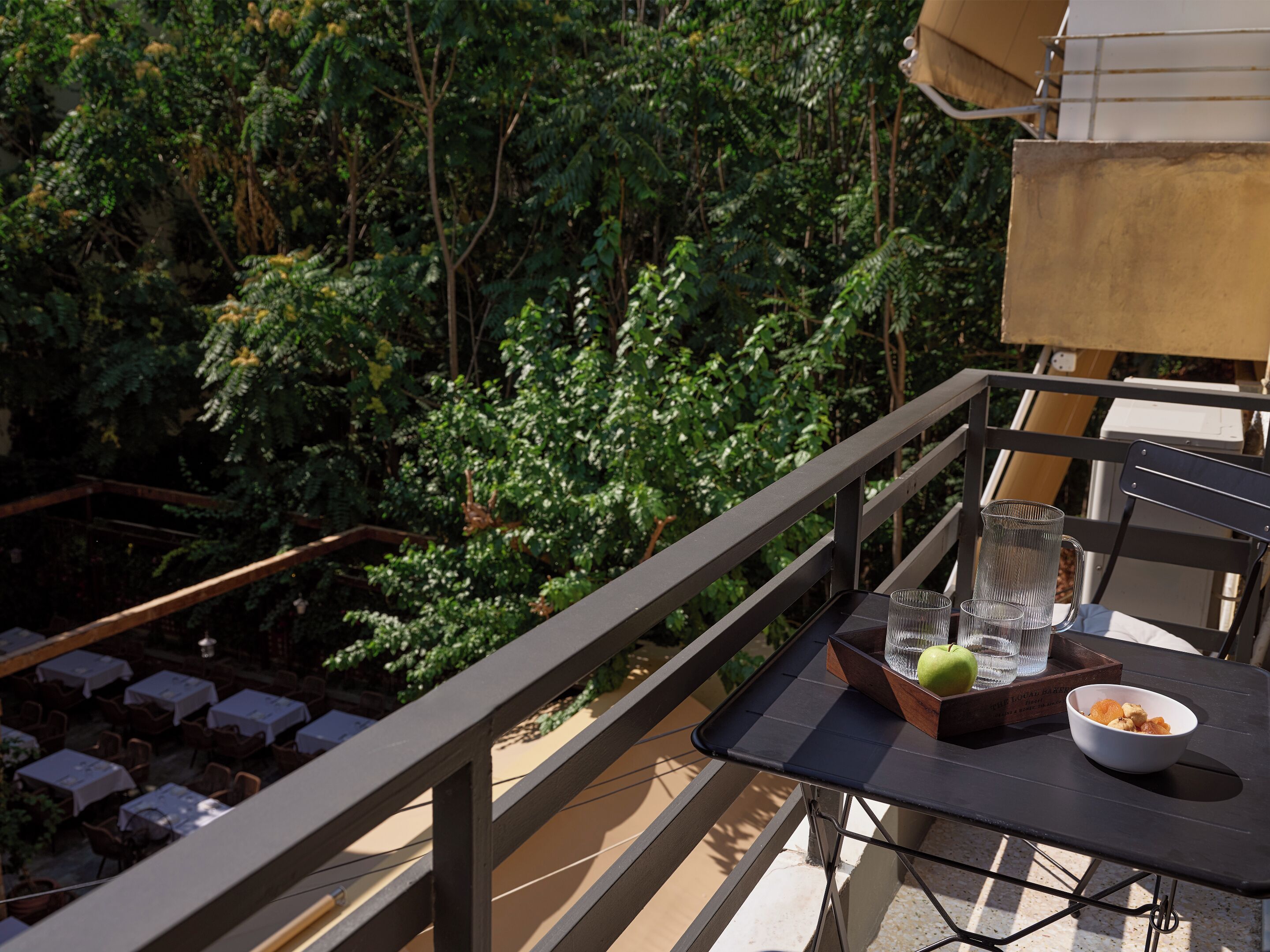 A balcony with a table, a chair, and a view of dense foliage.