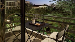 A balcony with a table set for two, a bottle of wine, and a tray of snacks.