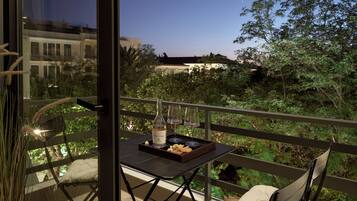 A balcony with a table set for two, a bottle of wine, and a tray of snacks.