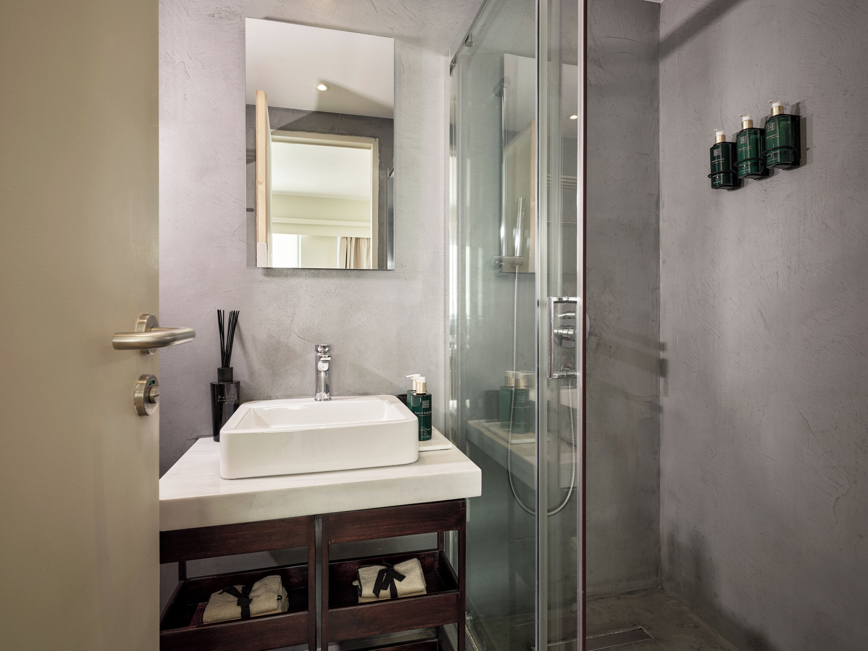 Une salle de bain moderne avec une douche à parois de verre, un lavabo blanc et un miroir au-dessus.