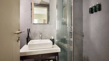 Une salle de bain moderne avec une douche à parois de verre, un lavabo blanc et un miroir au-dessus.