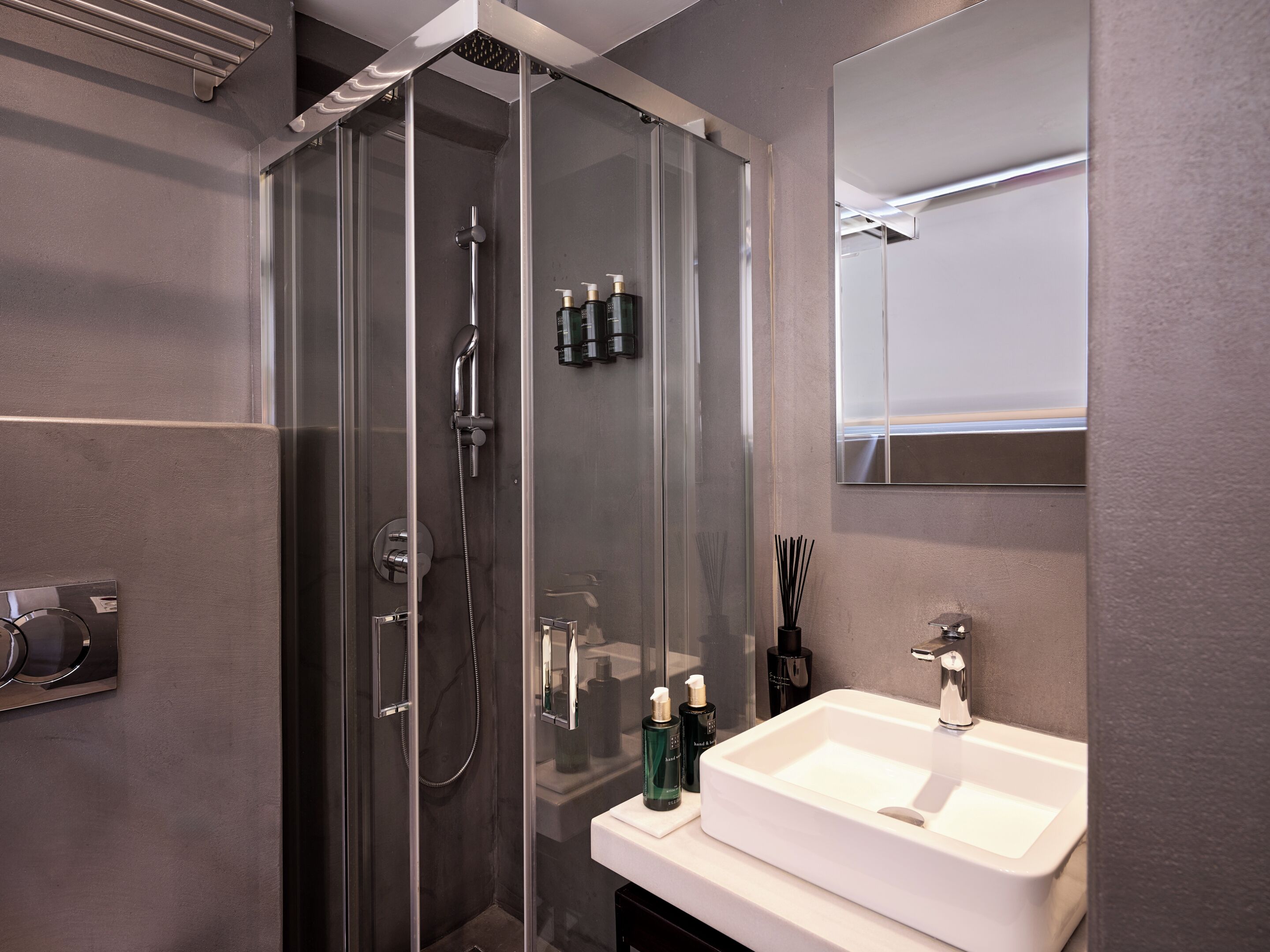 A modern bathroom with a glass-enclosed shower, a white sink, and a mirror above it.