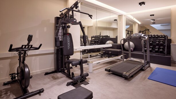 A home gym with a treadmill, elliptical, weight bench, and various exercise equipment.