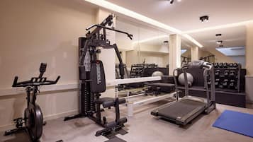 A home gym with a treadmill, elliptical, weight bench, and various exercise equipment.