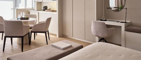A modern hotel room with a bed, a desk, and a dining area.