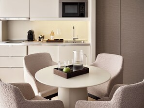 Une cuisine moderne équipée d’un four à micro-ondes, d’un évier et d’un coin repas avec une table ronde et deux chaises.